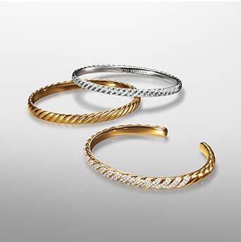 A set of three David Yurman Sculpted Cable Bracelets in gold and silver with and without diamonds.